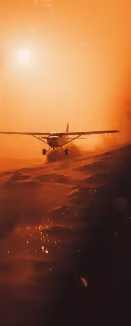 a small plane flying over a sand dune