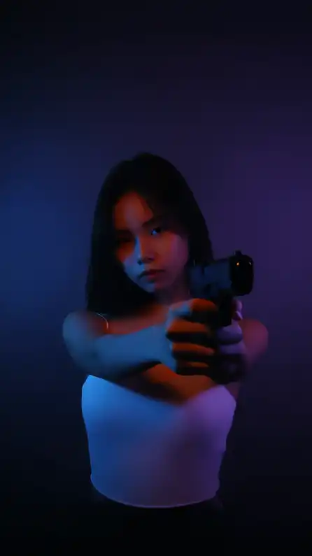 asian girl with prominently feminine body shape holding a gun towards the camera